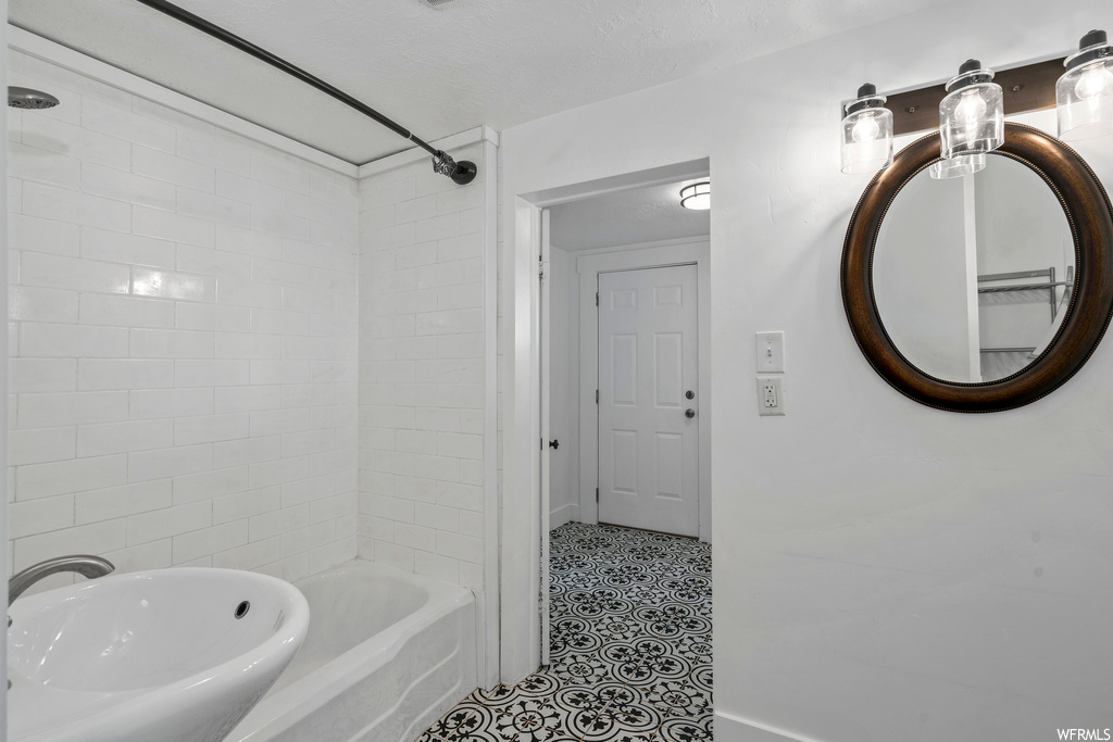 Bathroom with mirror, tub / shower combination, and sink