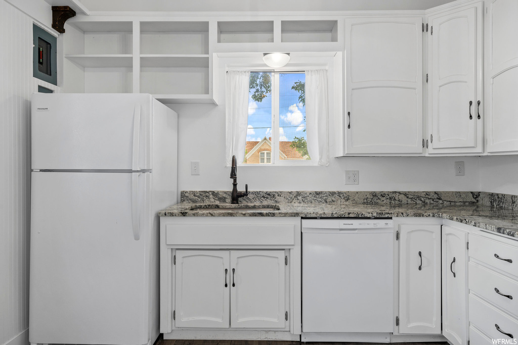 Kitchen with natural light, dishwasher, refrigerator, granite-like countertops, and white cabinets