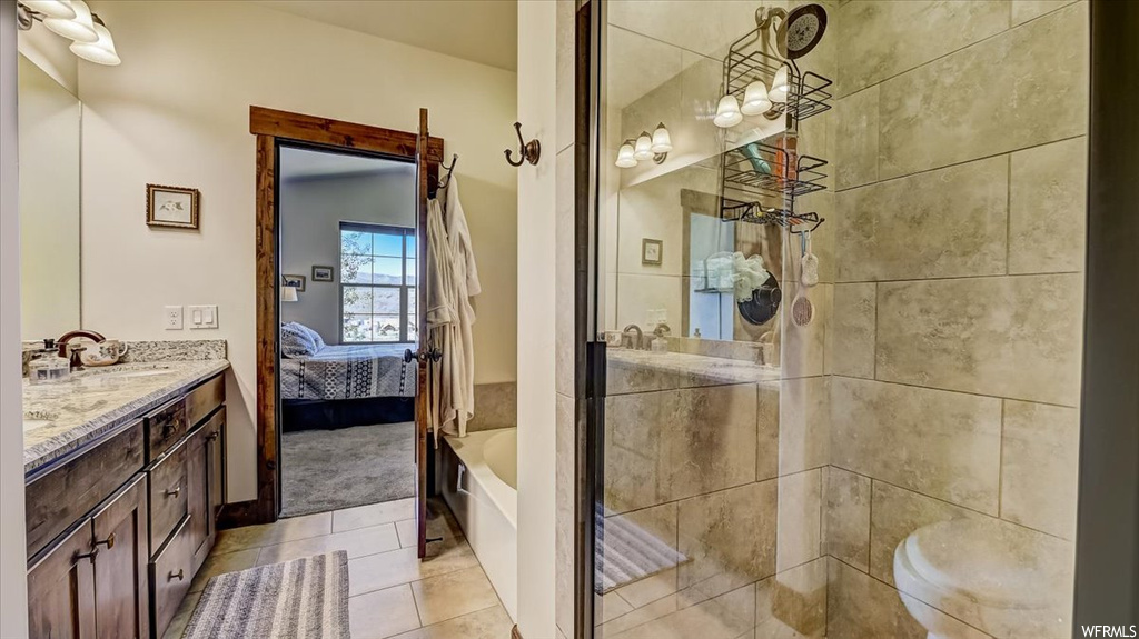 Bathroom featuring tile floors, multiple mirrors, a tub, double sink vanity, and toilet