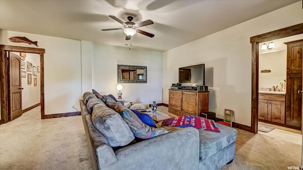 Carpeted living room with a ceiling fan and TV