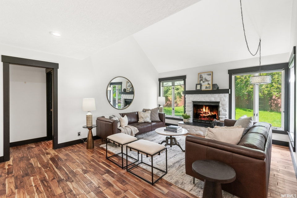 Living room featuring a fireplace, natural light, hardwood flooring, and lofted ceiling