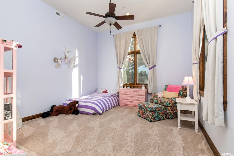 Carpeted bedroom featuring a ceiling fan and natural light