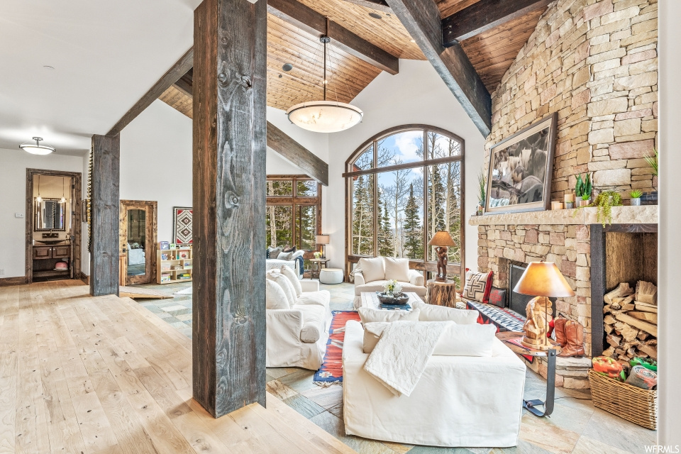 Interior space with a fireplace, vaulted ceiling with beams, a high ceiling, and hardwood flooring
