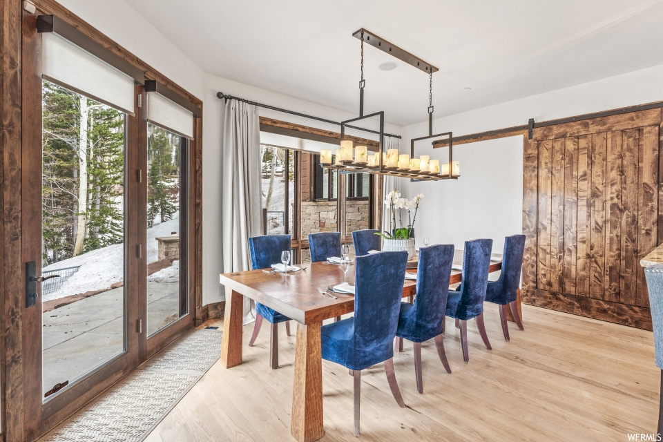 Hardwood floored dining space with a notable chandelier and natural light
