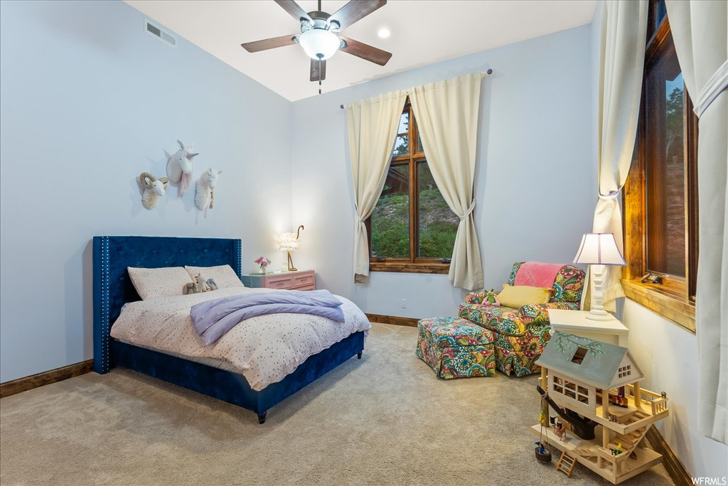 Carpeted bedroom featuring a ceiling fan and natural light