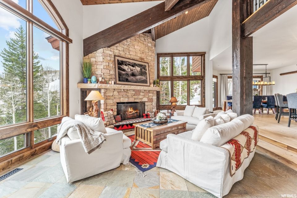 Tiled living room featuring a fireplace, a high ceiling, wood beam ceiling, and natural light