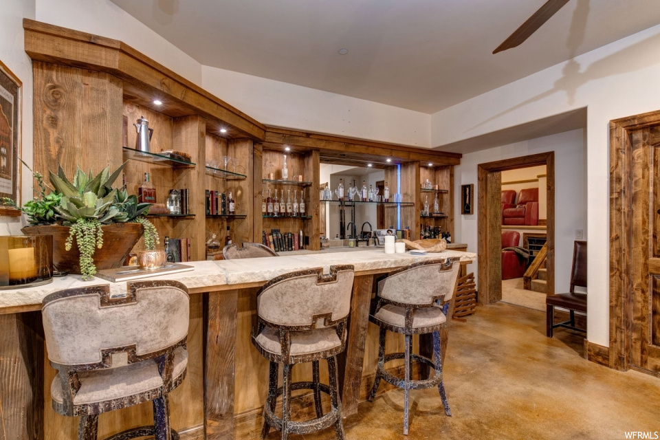 Bar with a kitchen breakfast bar, carpet, light granite-like countertops, and light flooring