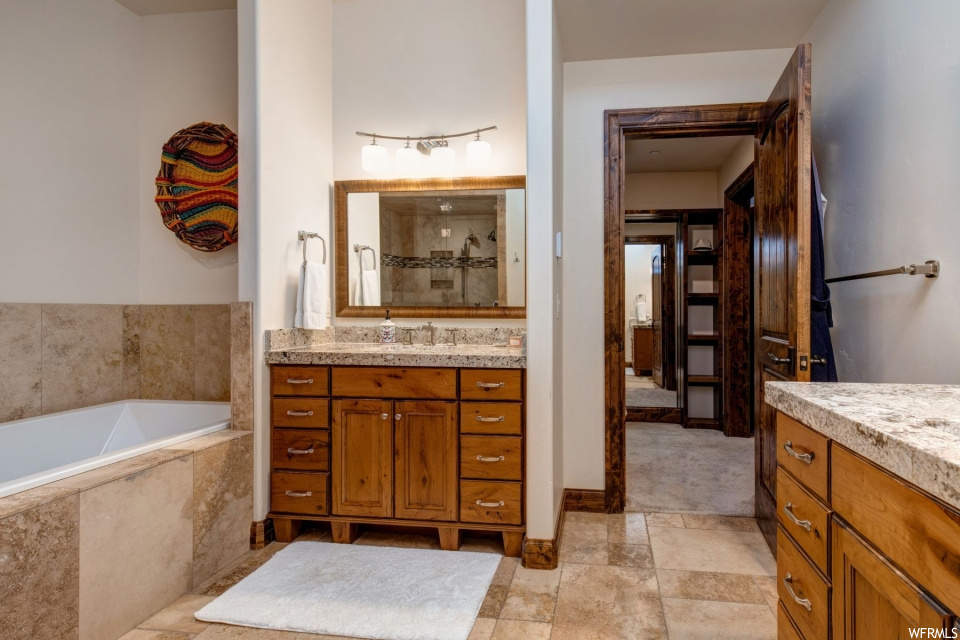 Bathroom featuring tile flooring, a bath, mirror, and vanity