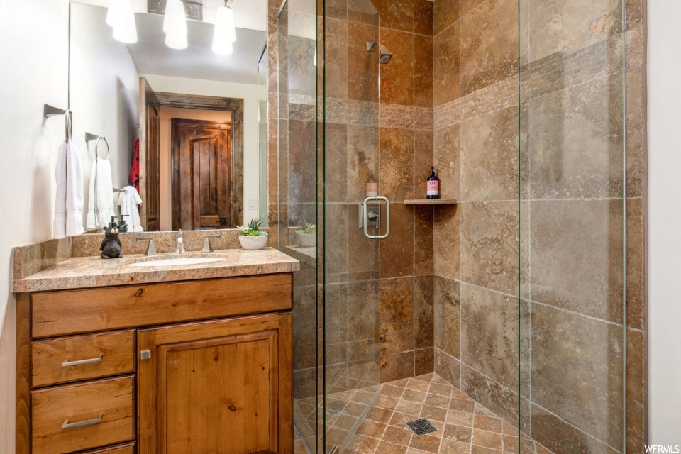 Bathroom featuring tile floors, shower with glass door, oversized vanity, and mirror
