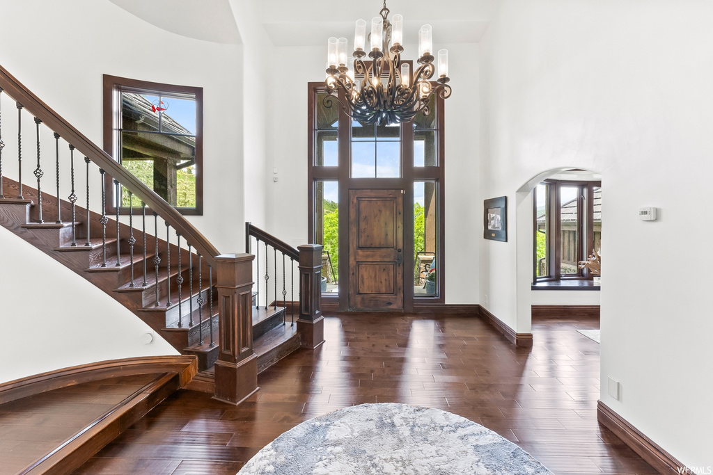 Wood floored foyer featuring plenty of natural light, a high ceiling, and a chandelier