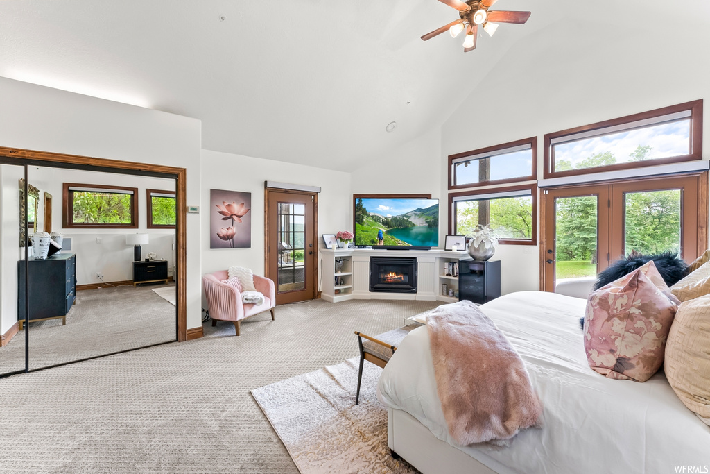 Carpeted bedroom featuring a ceiling fan, lofted ceiling, a high ceiling, a fireplace, natural light, and TV