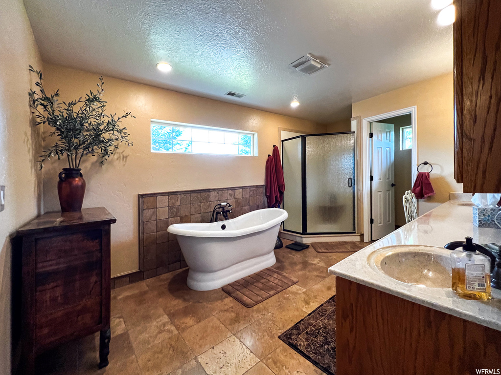 Bathroom featuring tile floors, vanity, and separate shower and tub enclosures