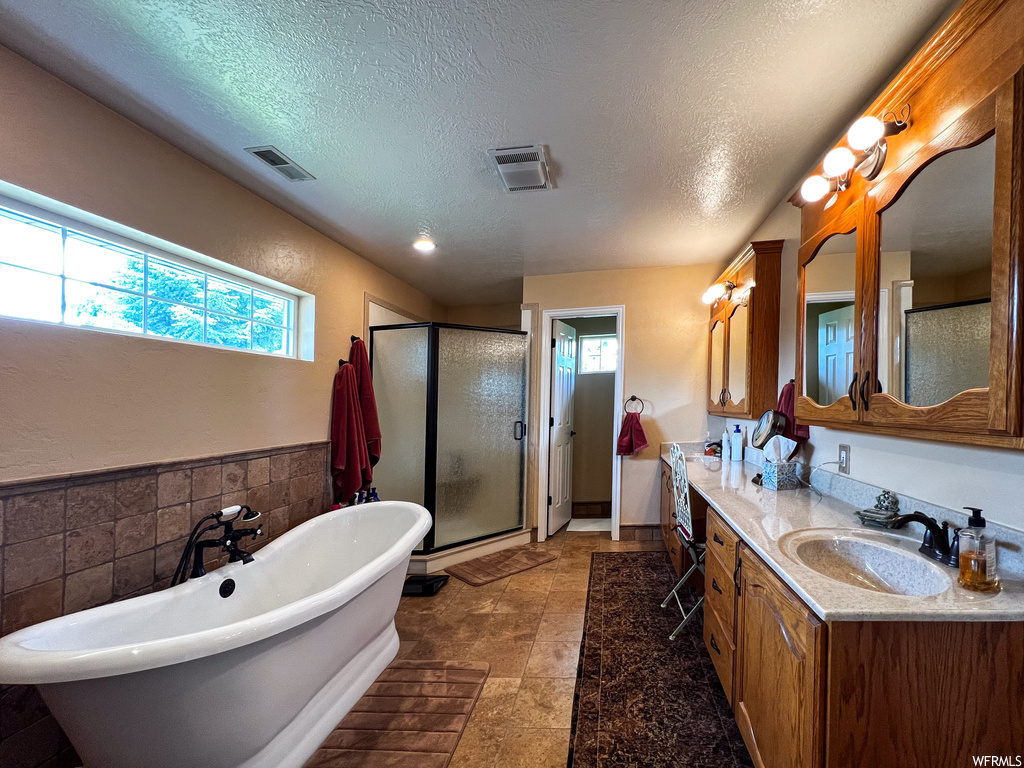 Bathroom featuring a wealth of natural light, tile flooring, mirror, double large sink vanity, and independent shower and bath