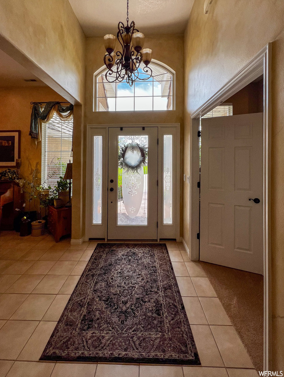 Foyer featuring a high ceiling, tile floors, and a notable chandelier
