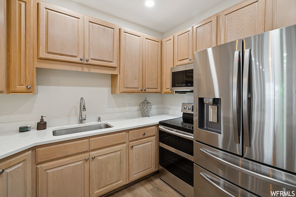 Kitchen with hardwood flooring, microwave, refrigerator, electric range oven, and light countertops