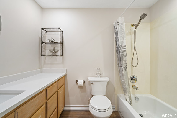 Full bathroom featuring hardwood floors, shower curtain, vanity, bath / shower combination, and toilet