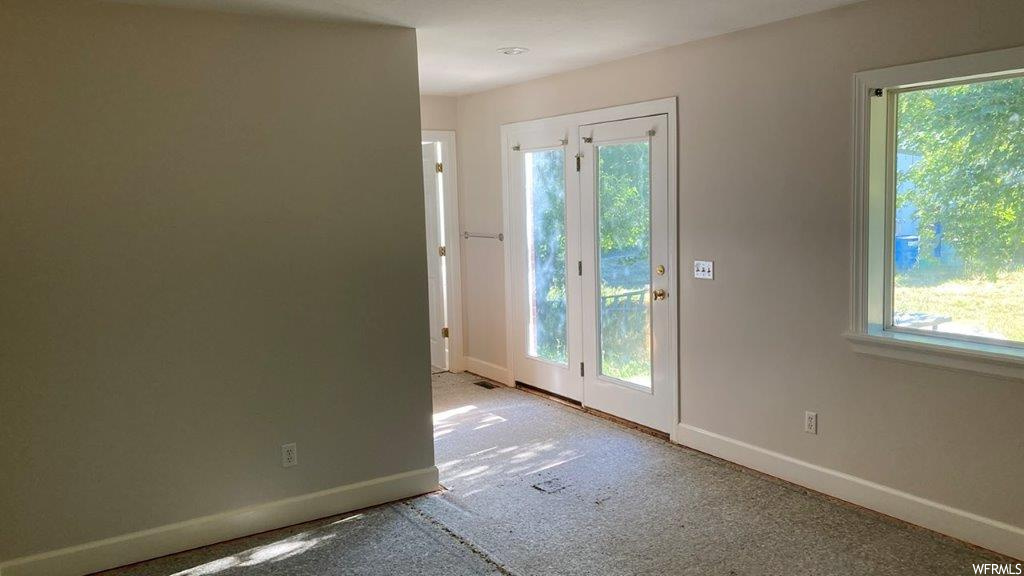 Doorway to outside featuring carpet and natural light