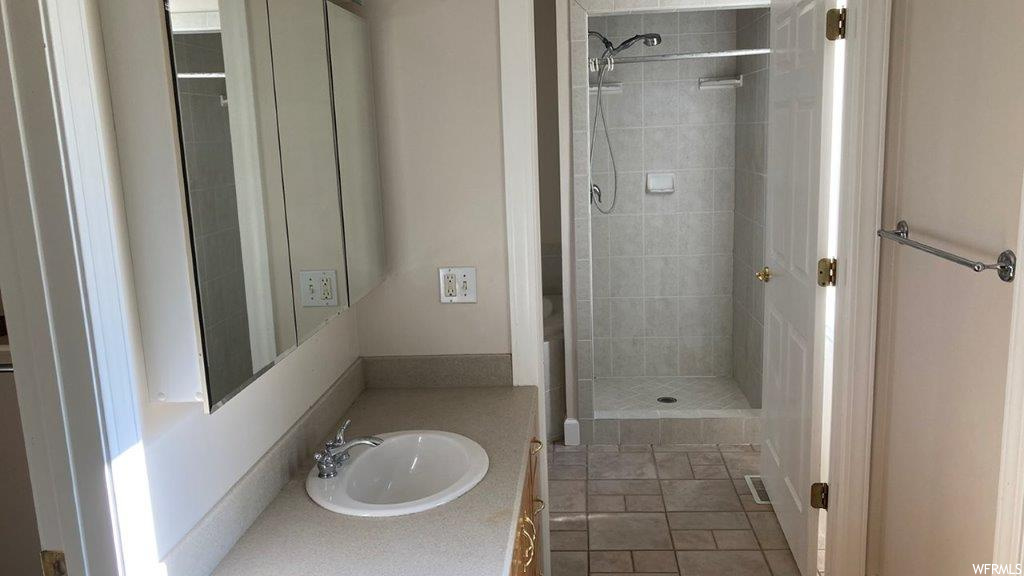 Bathroom featuring tile floors, a shower, mirror, and vanity