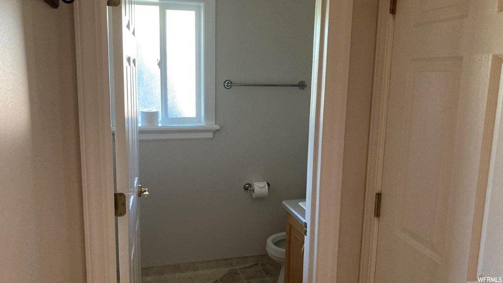 Half bath featuring tile floors, natural light, toilet, and vanity