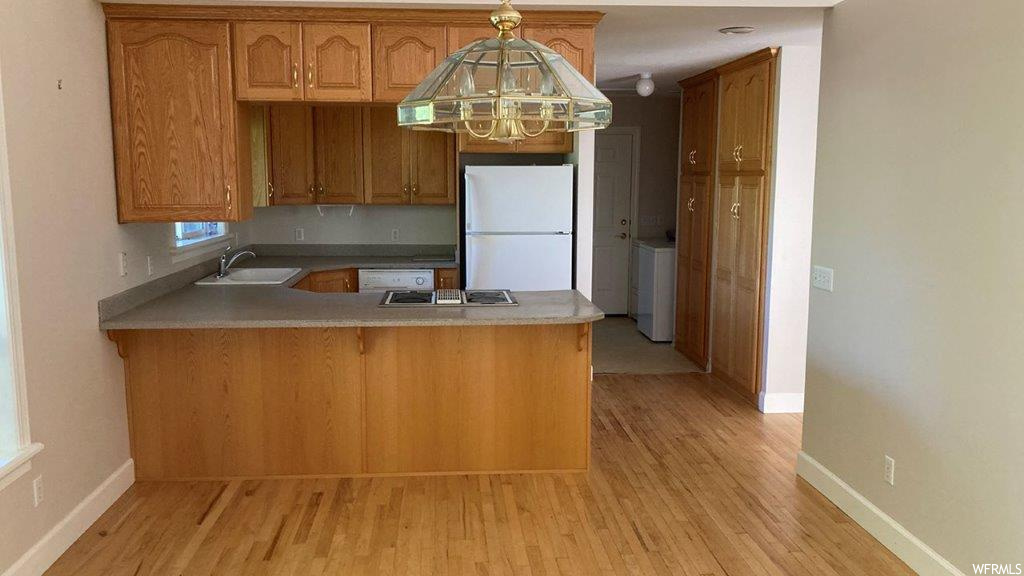 Kitchen with refrigerator, brown cabinets, and light hardwood flooring