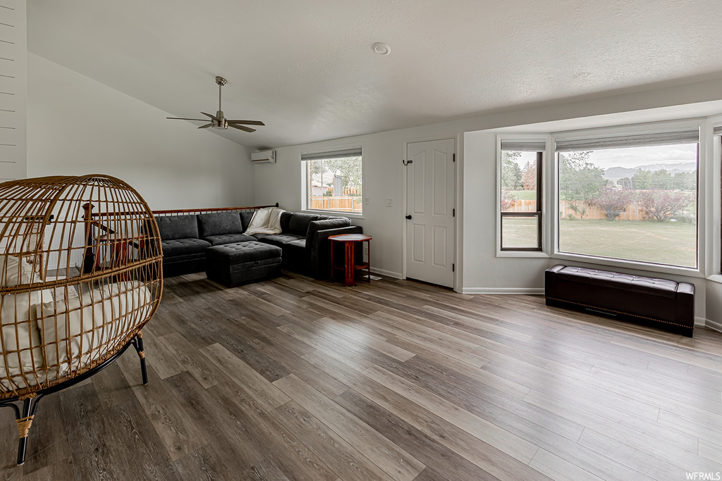 Hardwood floored living room featuring a ceiling fan and natural light