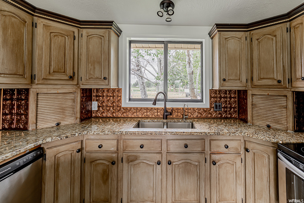 Kitchen featuring natural light, dishwasher, brown cabinetry, and dark granite-like countertops