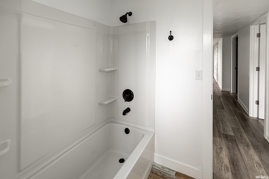 Bathroom with hardwood floors and shower / washtub combination