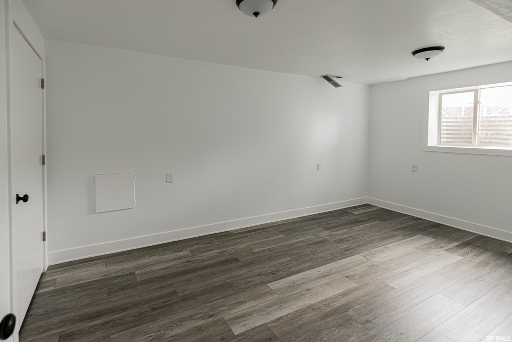 Hardwood floored empty room featuring natural light