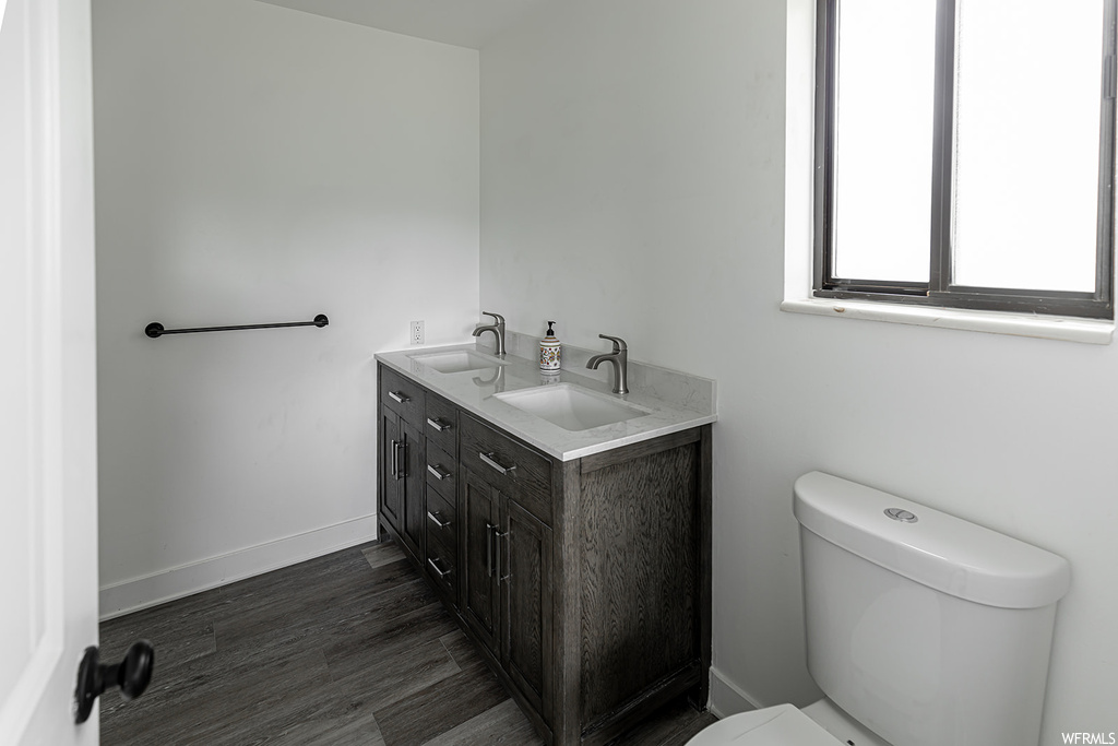 Half bath with natural light, toilet, and dual vanity