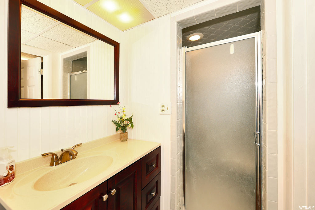 Bathroom with mirror, vanity, and shower with glass door