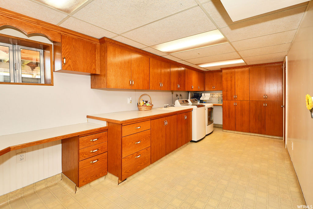 Kitchen with independent washer and dryer, light tile floors, brown cabinets, and light countertops