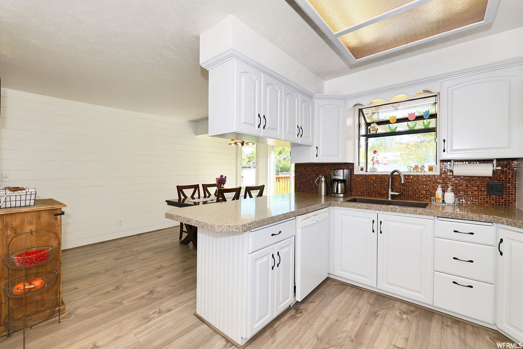 Kitchen with natural light, dishwasher, white cabinets, and light parquet floors