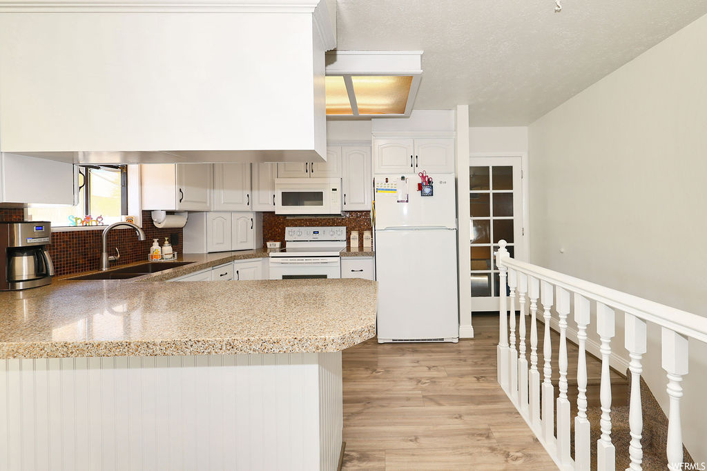 Kitchen with microwave, range oven, refrigerator, light countertops, light parquet floors, and white cabinetry