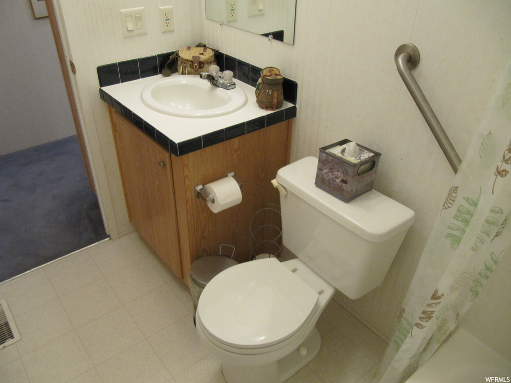 Bathroom featuring tile flooring, toilet, mirror, vanity, and shower curtain