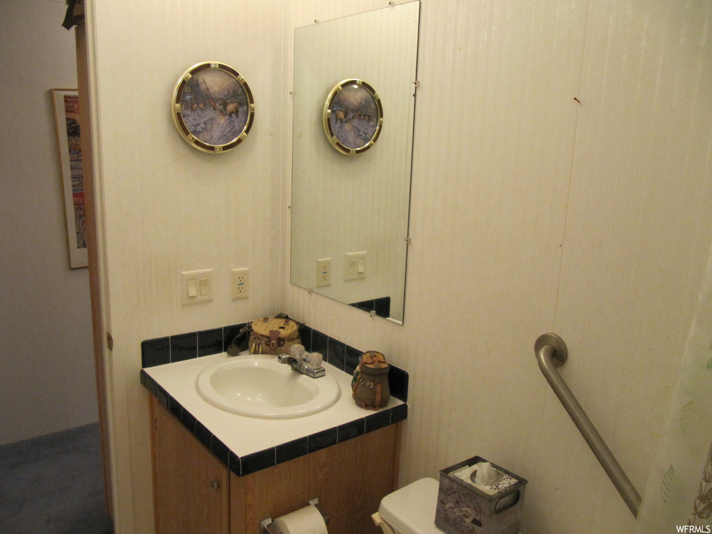 Half bath featuring toilet, mirror, and oversized vanity