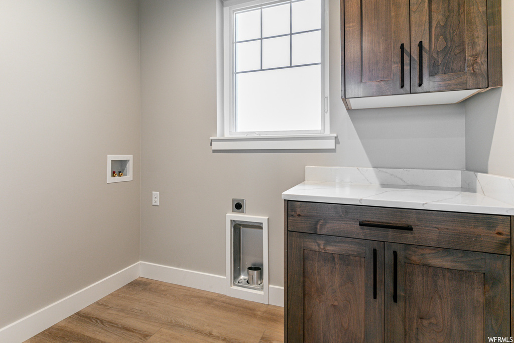 Washroom with plenty of natural light, light hardwood / wood-style flooring, hookup for an electric dryer, and washer hookup