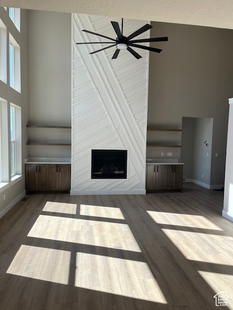 Unfurnished living room with dark hardwood / wood-style flooring, a towering ceiling, and a fireplace