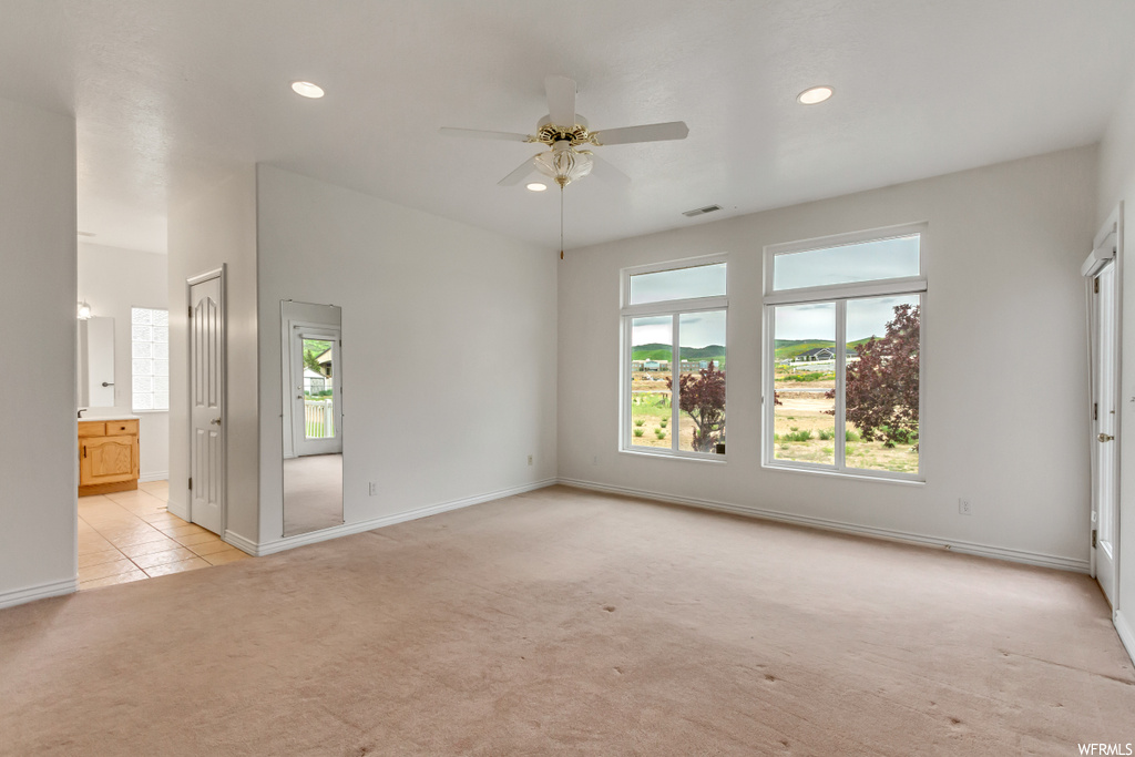 Empty room featuring natural light, a ceiling fan, and carpet