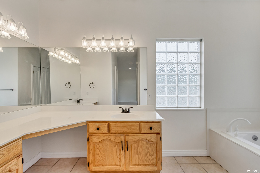 Bathroom featuring tile floors, vanity, mirror, and a bathtub