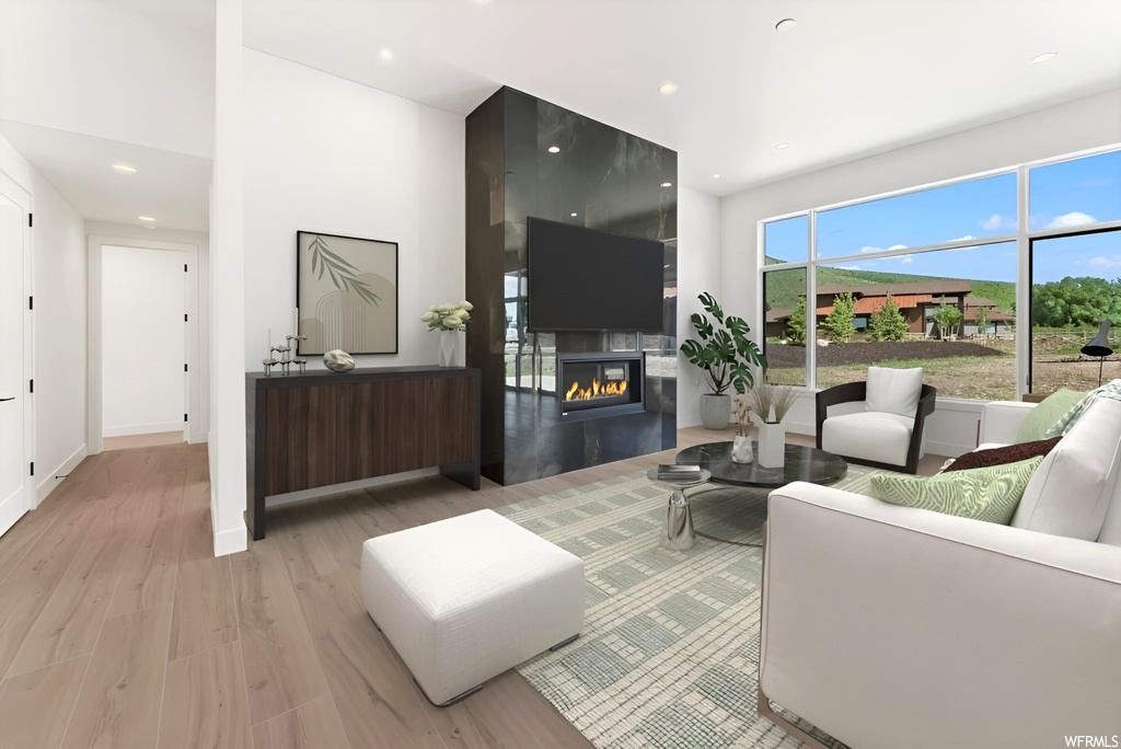 Hardwood floored living room with a fireplace, natural light, and TV