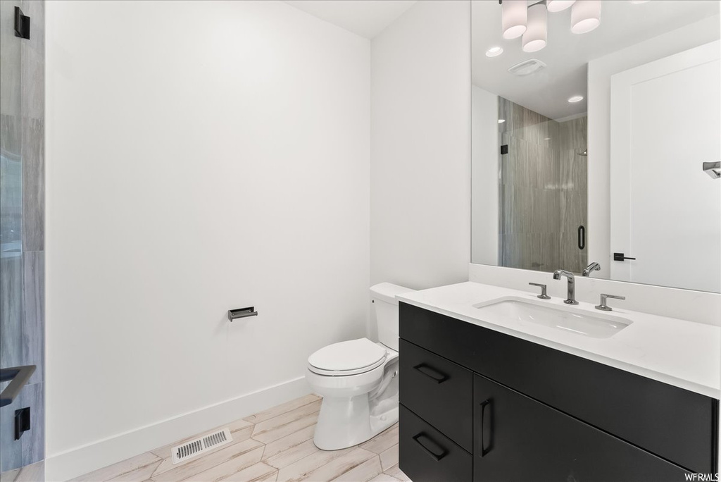 Half bath with tile floors, toilet, mirror, and vanity