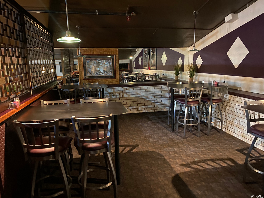 Bar featuring a breakfast bar, dark floors, dark brown cabinetry, pendant lighting, and dark countertops