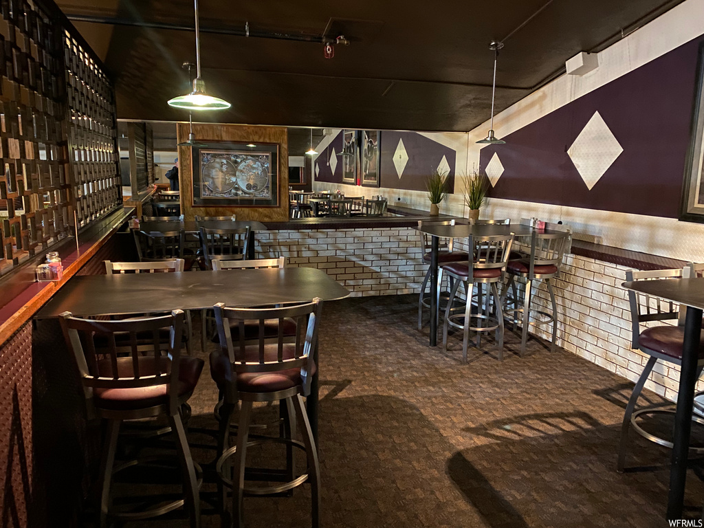 Bar featuring a kitchen breakfast bar, dark countertops, dark brown cabinetry, dark flooring, and pendant lighting