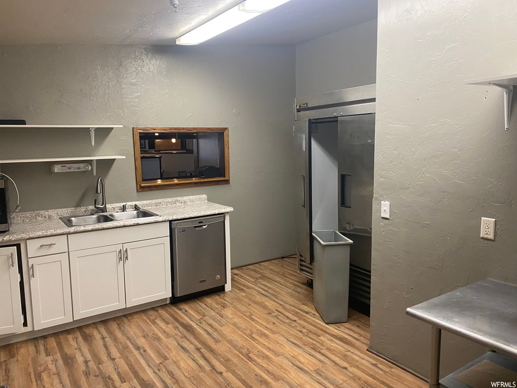 Kitchen featuring dishwasher, light countertops, and light hardwood flooring