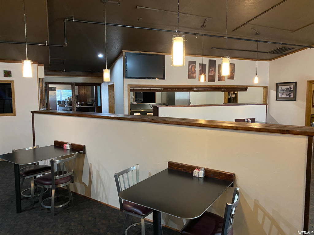 Kitchen featuring a breakfast bar, TV, pendant lighting, and dark countertops