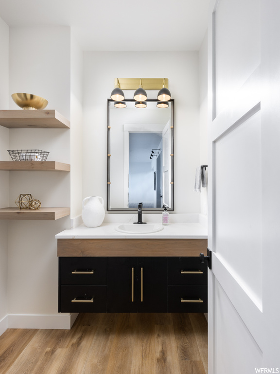 Bathroom featuring oversized vanity, mirror, and light hardwood floors