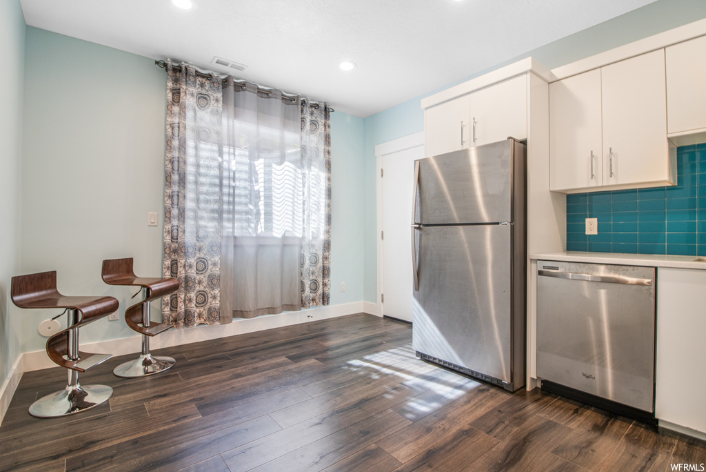 Kitchen with refrigerator, dishwasher, dark hardwood flooring, and white cabinets