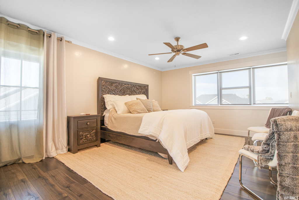 Hardwood floored bedroom with multiple windows and a ceiling fan