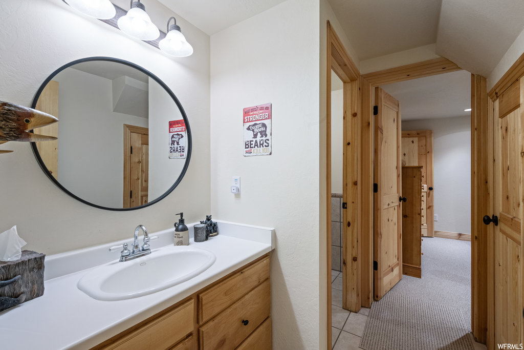 Bathroom with tile flooring, vanity with extensive cabinet space, and mirror