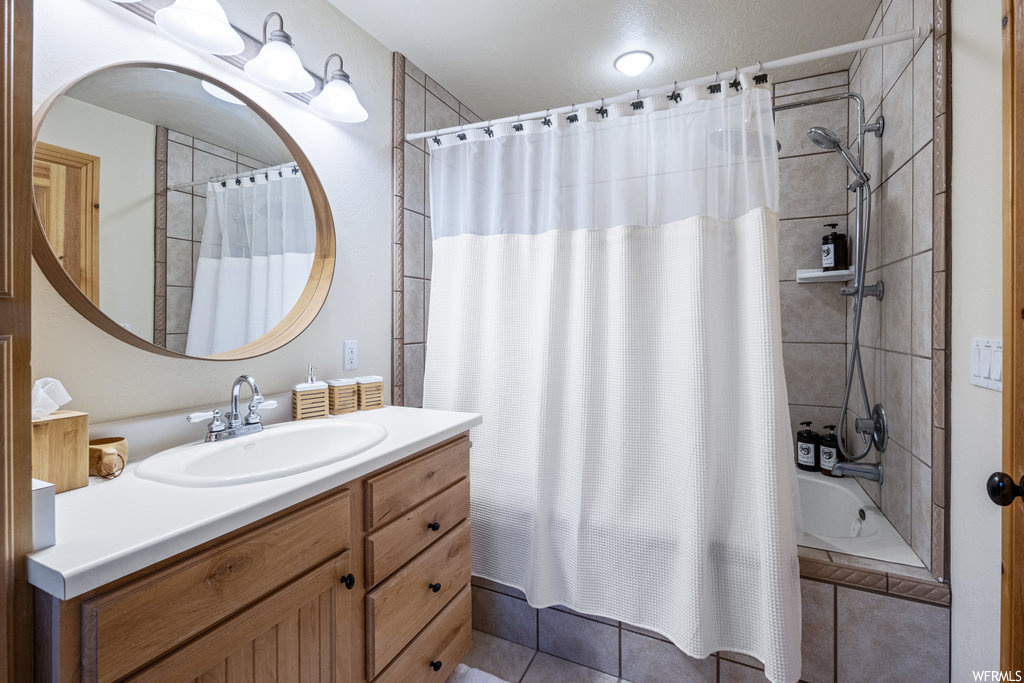 Bathroom featuring tile floors, vanity, mirror, and shower curtain